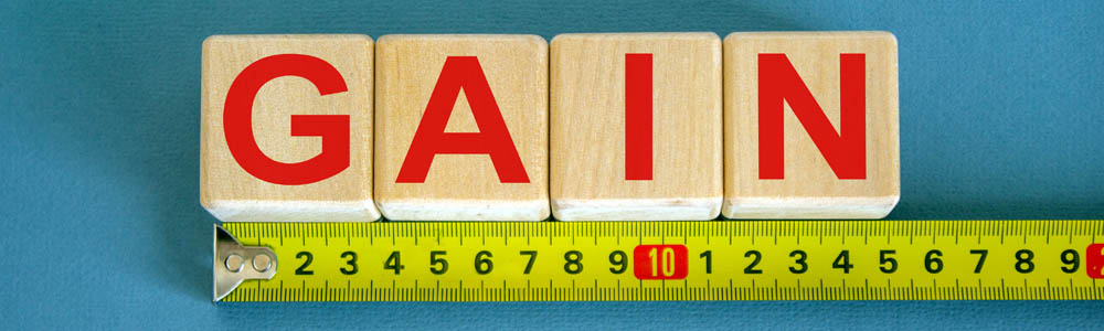 Small wooden toy blocks spelling out GAIN with tape measure underneath